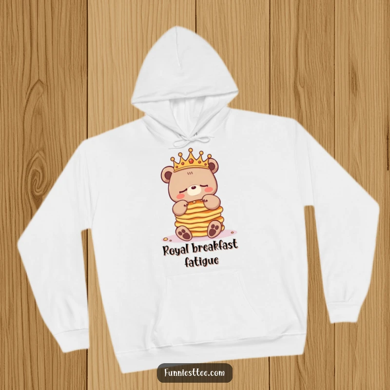 Funny sleepy bear hoodie with a crowned bear character attempting to balance a mountain of pancakes, looking adorably overwhelmed.