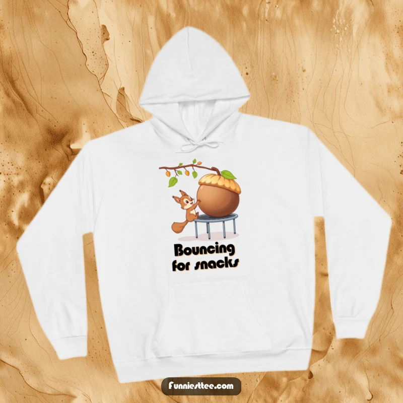 Funny hoodie depicting a mischievous squirrel attempting to steal a giant acorn using a trampoline, highlighting comical heist antics.