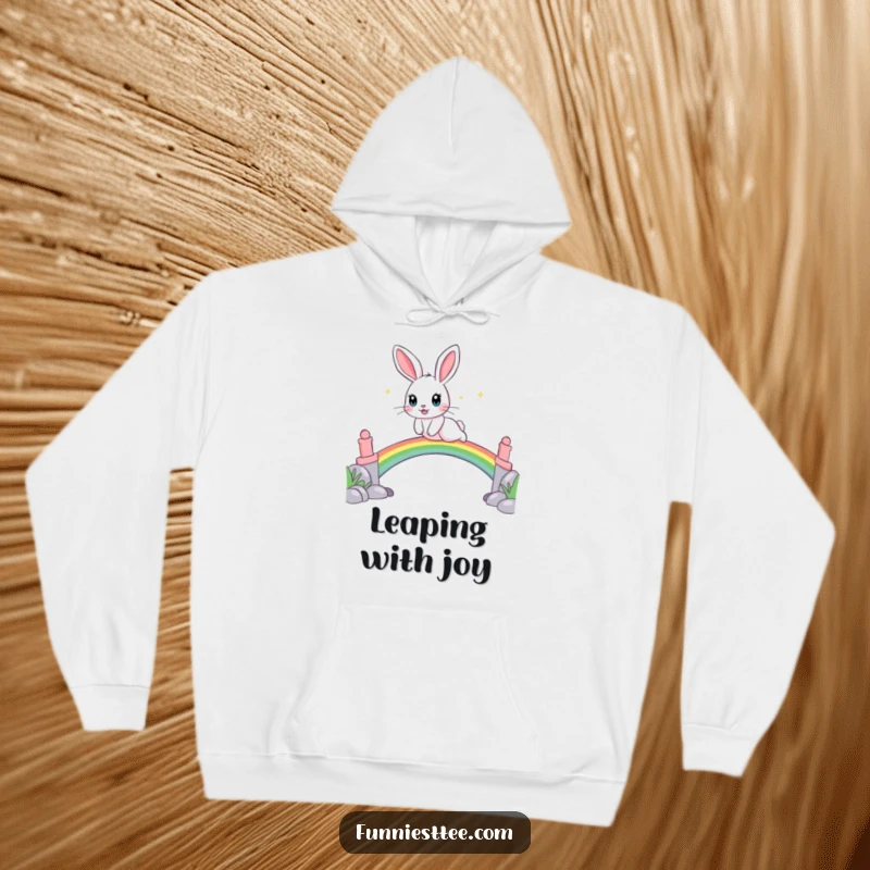 Funny hoodie featuring a playful rabbit with sparkling eyes leaping over a rainbow bridge, offering cozy magic.